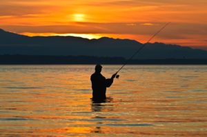 10554836 - silhouette of a fisherman with a fishing pole at sunset.
